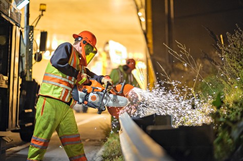 A MnDOT worker replaces a section of broken guardrail.