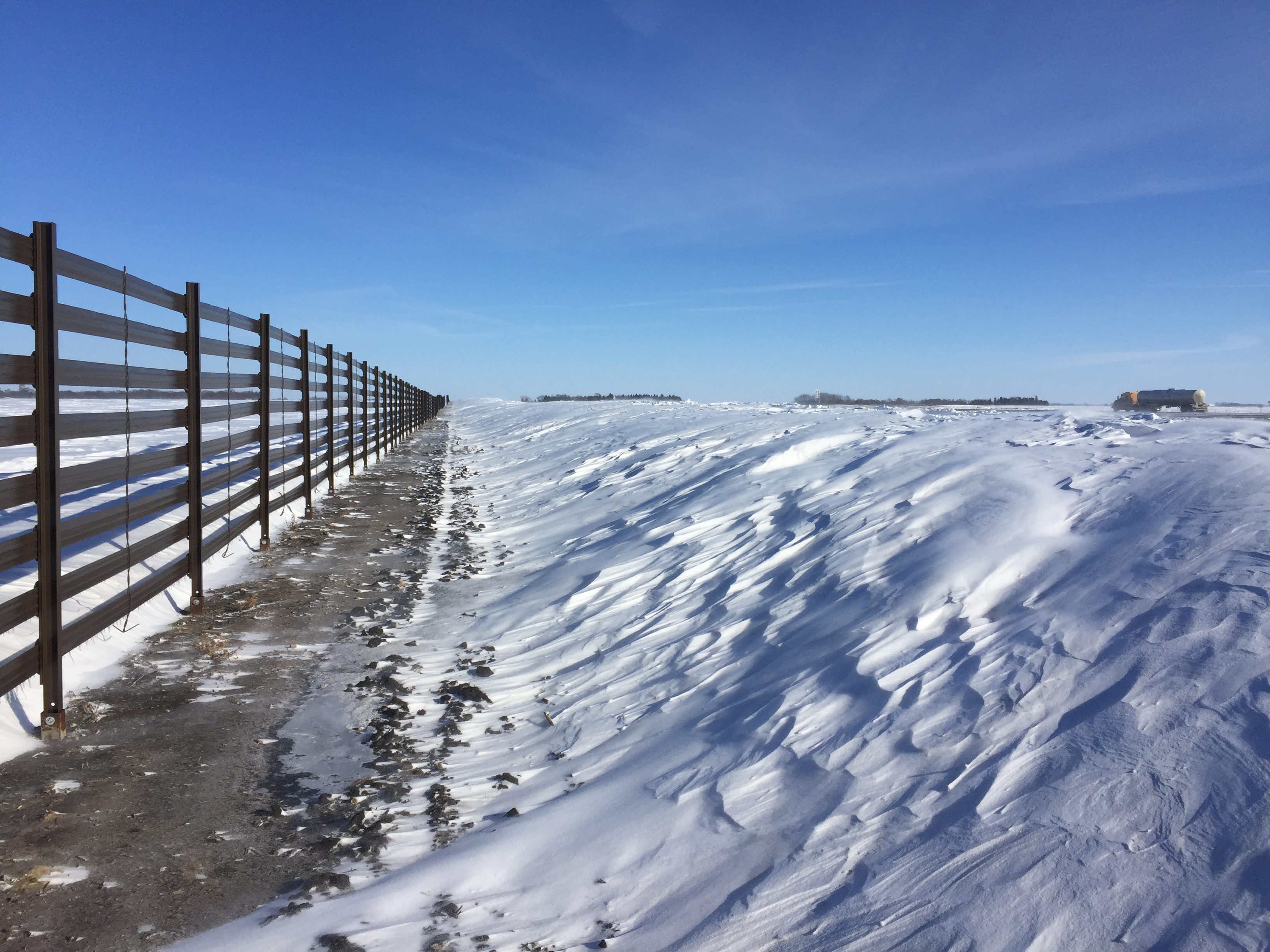 A permanent snow fence along a rural highway.