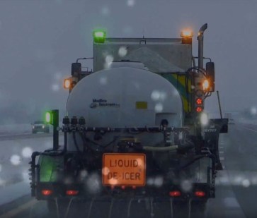 Maintenance truck applying liquid de-icer on highway