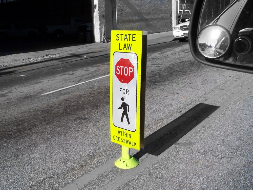 In-street pedestrian crossing sign with the message “State law: Stop for pedestrians within crosswalk.”