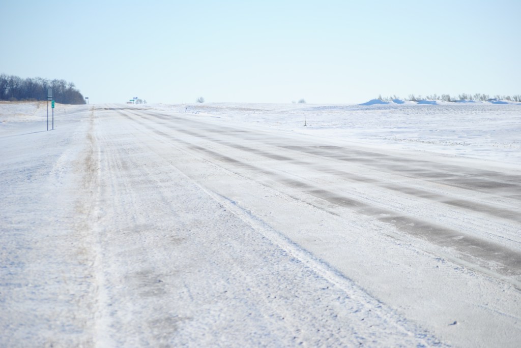 Cross-road snow drifting at a rural control site on a clear day.