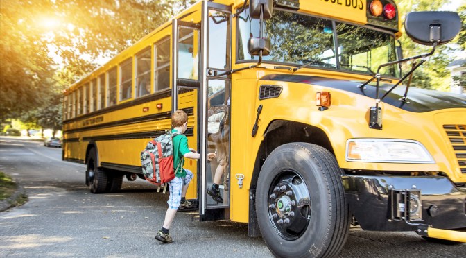Children boarding a school bus in the morning.]