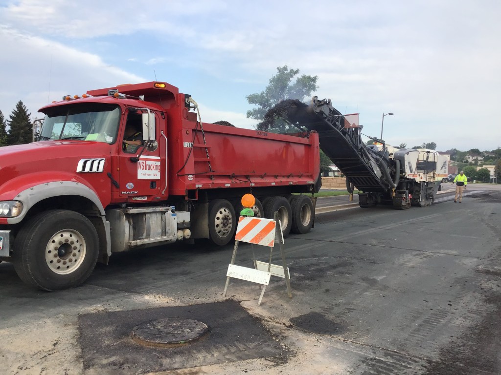 A truck and other equipment engaged in a road repaving operation.