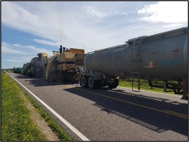 A convoy of paving equipment on a road.