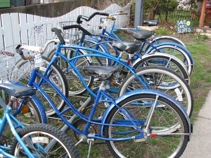 A line of parked bikes next to a sidewalk.