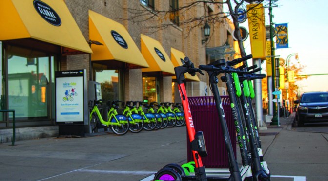 Colorful scooters parked on an urban sidewalk.