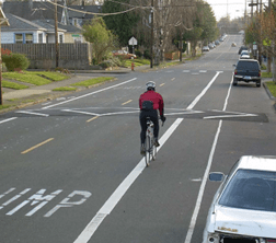 A cyclist approaching a speed bump on a road.