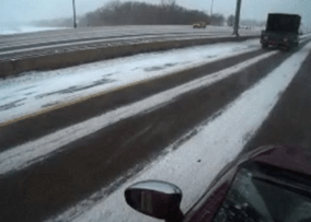 Wheel tracks on a snow-covered road after a heavy snowfall. Lane markers are covered with snow and not visible. 