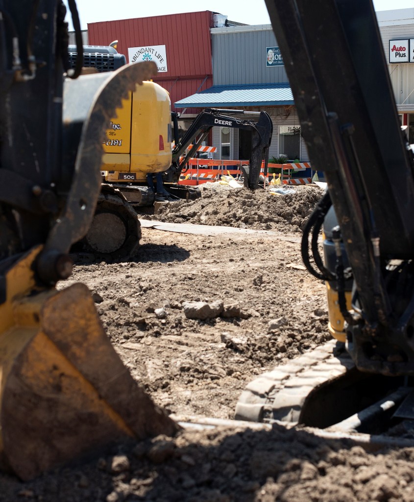 Road construction with businesses in background.