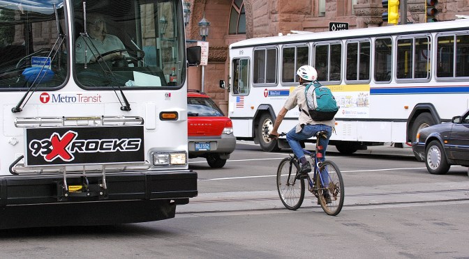 city street with cars, buses and biker