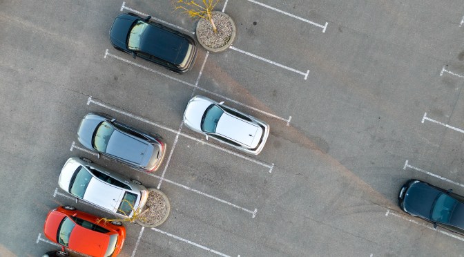 Few cars occupy a parking lot with spaces striped in white paint.