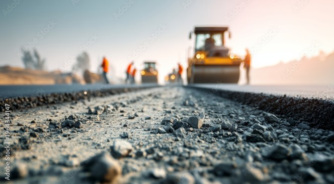 Fresh pavement is applied over a layer of gravel.